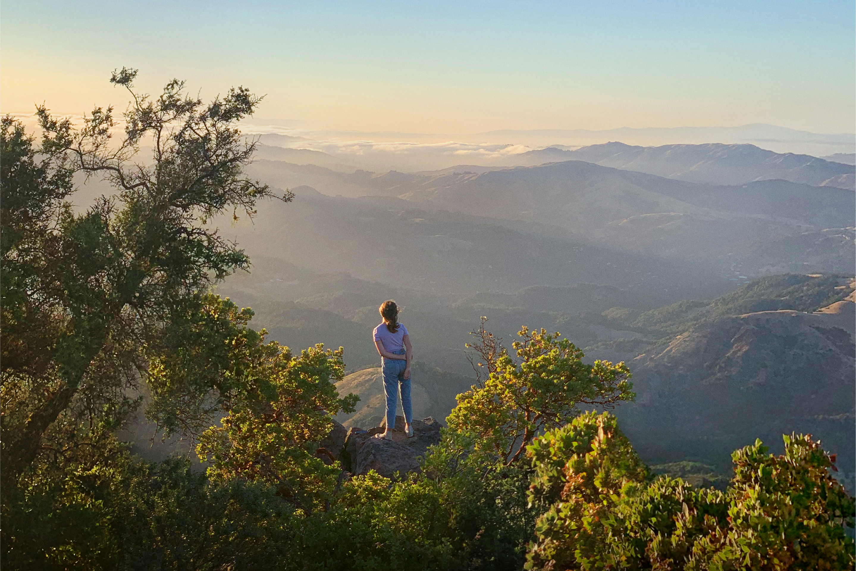 A woman gazes across a mountain range. 